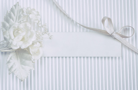 tender boutonniere, blank tag, white silk ribbon bow, on fluted paper, wedding cardの写真素材