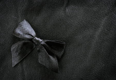 natural texture black leather background with silk ribbon bowの写真素材