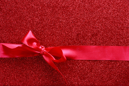 valentine's day, holiday shiny textured background with silky red ribbon tied in bow.の写真素材