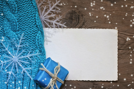 Winter Christmas background with turquoise knitted hat and gift, snowflake, paper blankの写真素材
