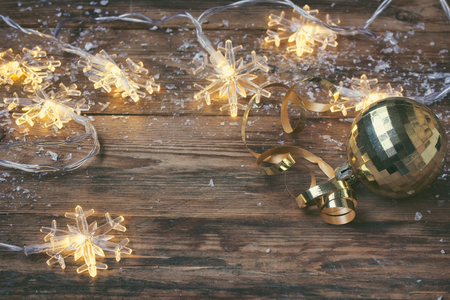 christmas, new year greeting card, garland light snowflake border and golden ball on wooden table, selective focusの写真素材