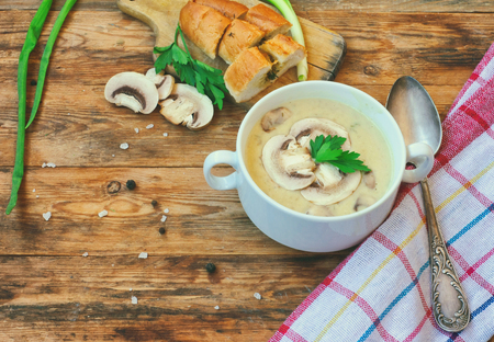 homemade cheese cream soup with champignons in white bowl, on wooden table, rustic styleの写真素材
