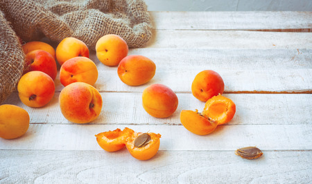 ripe apricots on wooden table, rough burlap sack, close-up, selective focus