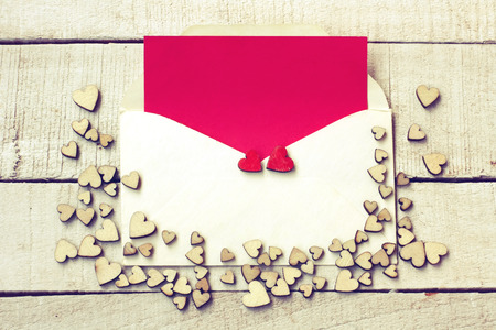 Valentine's day congratulation card, bunch of different plywood hearts, envelope with blank red paper on  white wooden tableの写真素材