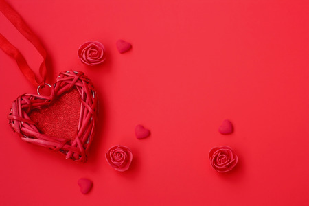 Valentine wicker heart, on ribbon, roses on red background. Valentines day composition, vintage...