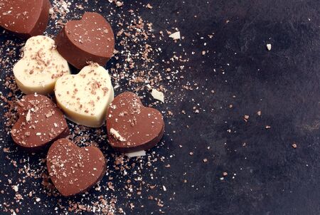 Valentines day background, home made chocolate dark and white hearts on black shabby surfaseの写真素材