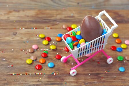 Easter chocolate egg, colorful candy on wooden table. Easter sale concept. Delicious dessert holiday...