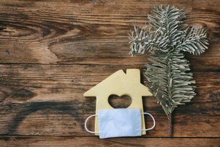 small toy house in medical mask, wood background, stay home, quarantine conceptの写真素材