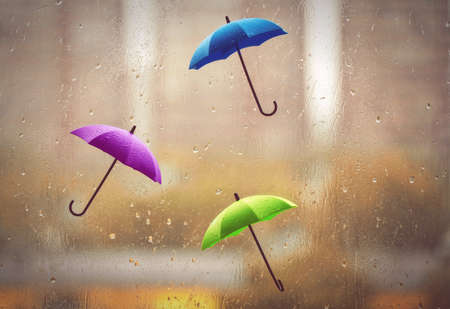 abstract autumn background, three wet umbrellas, rain outside window