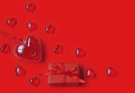 valentine day, transparent hearts and gift box with bow on red paper background, top view, space for textの写真素材