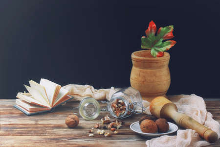 walnuts in glass jar on wooden table, mortar with pestle, retro style, selective focus