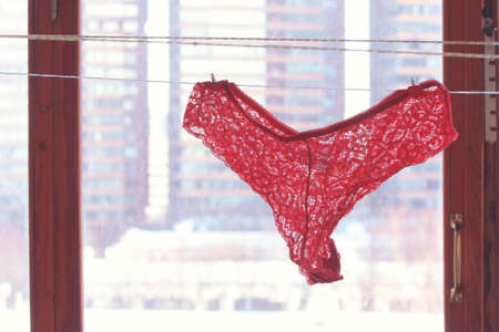red lace panties hanging on rope near the window, valentines day and womens day themeの写真素材