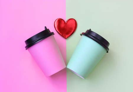 two paper cup with coffee, pink and green on paper background, red heart, valentines day themeの写真素材