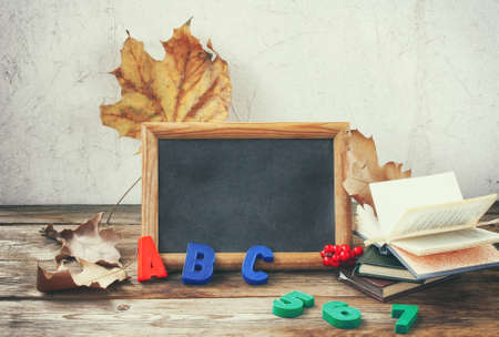 knowledge day background, letters and numbers, dry leaves, charcoal board and books on wooden table, autumn themeの写真素材