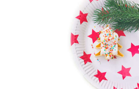 Christmas decoration, marshmallows in shape of Christmas tree with confectionery sprinkles on paper plate with red star, fir branches, white background, isolatedの写真素材