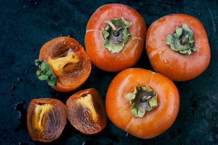 sweet ripe persimmon, cut into slices close-up on black table, top viewの写真素材