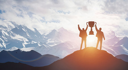 Silhouette of business people holding trophy against snowy mountains under sunlightの素材