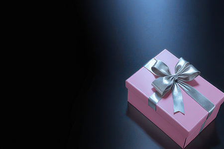 Pink gift box with silver ribbon on black background, copy space.の素材