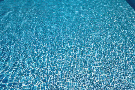 Blue pool water with sun reflections. Swimming pool background. Texture