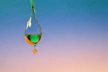 Water drop falling and colliding with another one on blue background.の素材