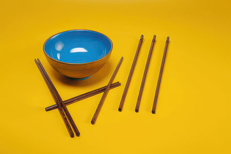 Ceramic bowl and chopsticks on a yellow background. Copy space.の素材