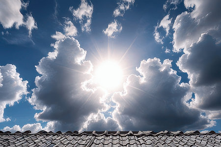 roof of a house against the blue sky with clouds and sunの素材