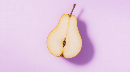 Ripe yellow pear cut in half on a pink background, top viewの素材