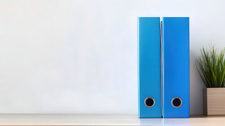 Blue office folders on a desk in front of a white wall.の素材
