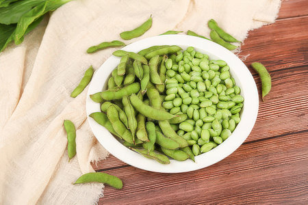 Green soybeans in a bowl on wooden background. Top view.の素材