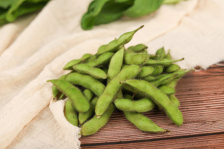 Green soybeans on a wooden table with a linen cloth, close upの素材