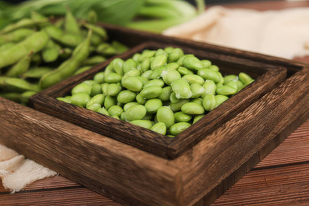 Green soybeans in a wooden bowl on a brown wooden background.の素材