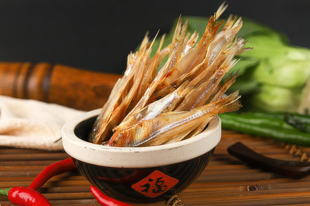 Dried fish in a bowl on a wooden table with chopsticksの素材