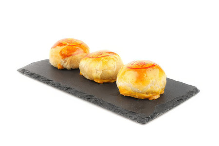 Three pastries on a black slate plate isolated on white backgroundの素材