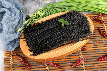 Black dry spaghetti with green onion and chili pepper on a wooden backgroundの素材