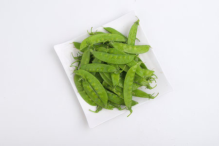 Pea pods on a white plate isolated on a white background.の素材