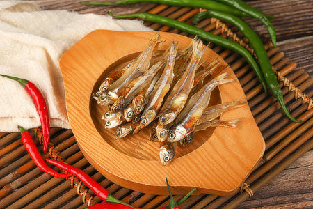Dried anchovies in wooden bowl with chili pepper on bamboo matの素材