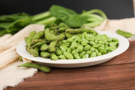 Green soybeans in a white plate on a wooden table, healthy foodの素材