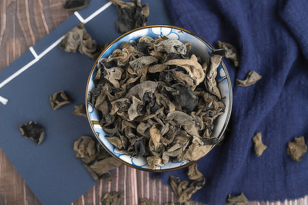 Dried black fungus in a bowl on a wooden background, top viewの素材