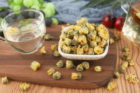 Dried chrysanthemum tea in glass cup on wooden boardの素材