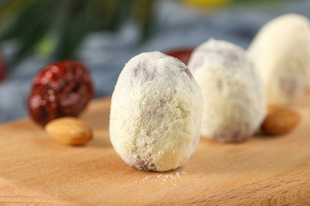 Delicious coconut candies on wooden board, closeup. Delicious dessertの素材