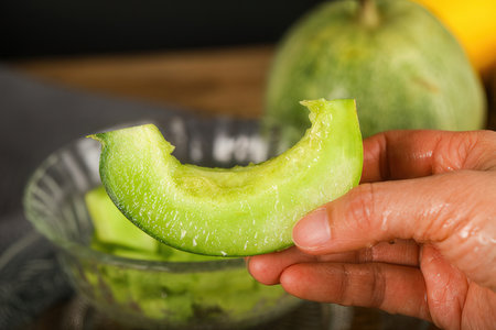 Sliced melon in a glass bowl on a wooden tableの素材