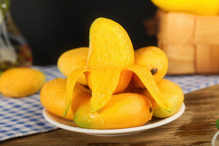 Ripe mangoes on a plate on a wooden table, closeupの素材