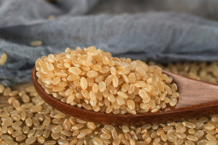 Raw brown rice in a wooden spoon on a wooden table, selective focus.の素材