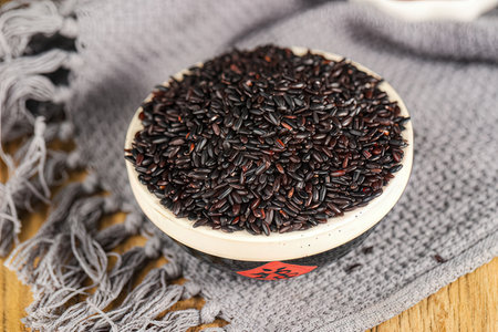 black rice in a bowl on a wooden table with a gray scarfの素材