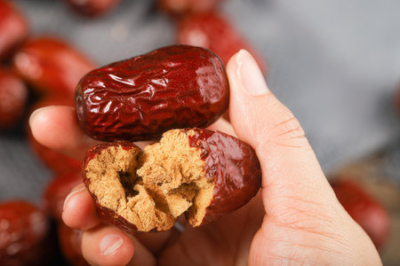 Closeup of a woman's hand holding a dried date fruit.の素材