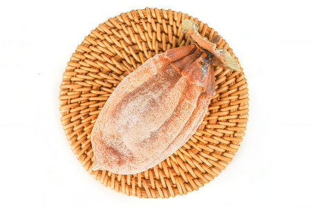 Dried persimmon on a wicker plate isolated on white backgroundの素材