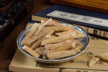Chinese herbal medicine in a bowl on a wooden table with books.の素材
