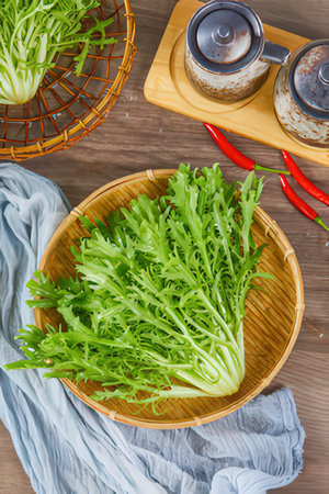 Fresh green arugula leaves in bamboo basket on wooden table.の素材