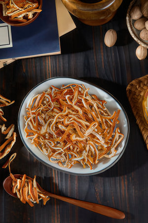 Dried chanterelle mushrooms in a bowl on a wooden tableの素材