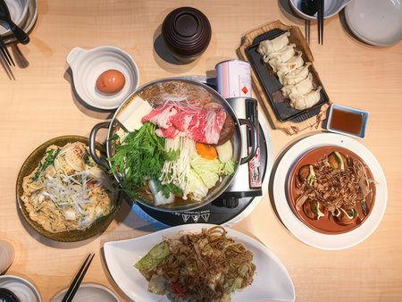 Japanese hot pot with beef, vegetables, noodles and sauce on tableの素材